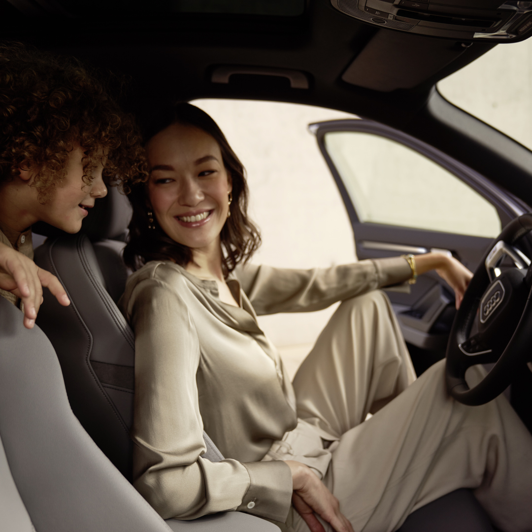 Frau und Kind sitzen in einem Audi mit offener Fahrertür