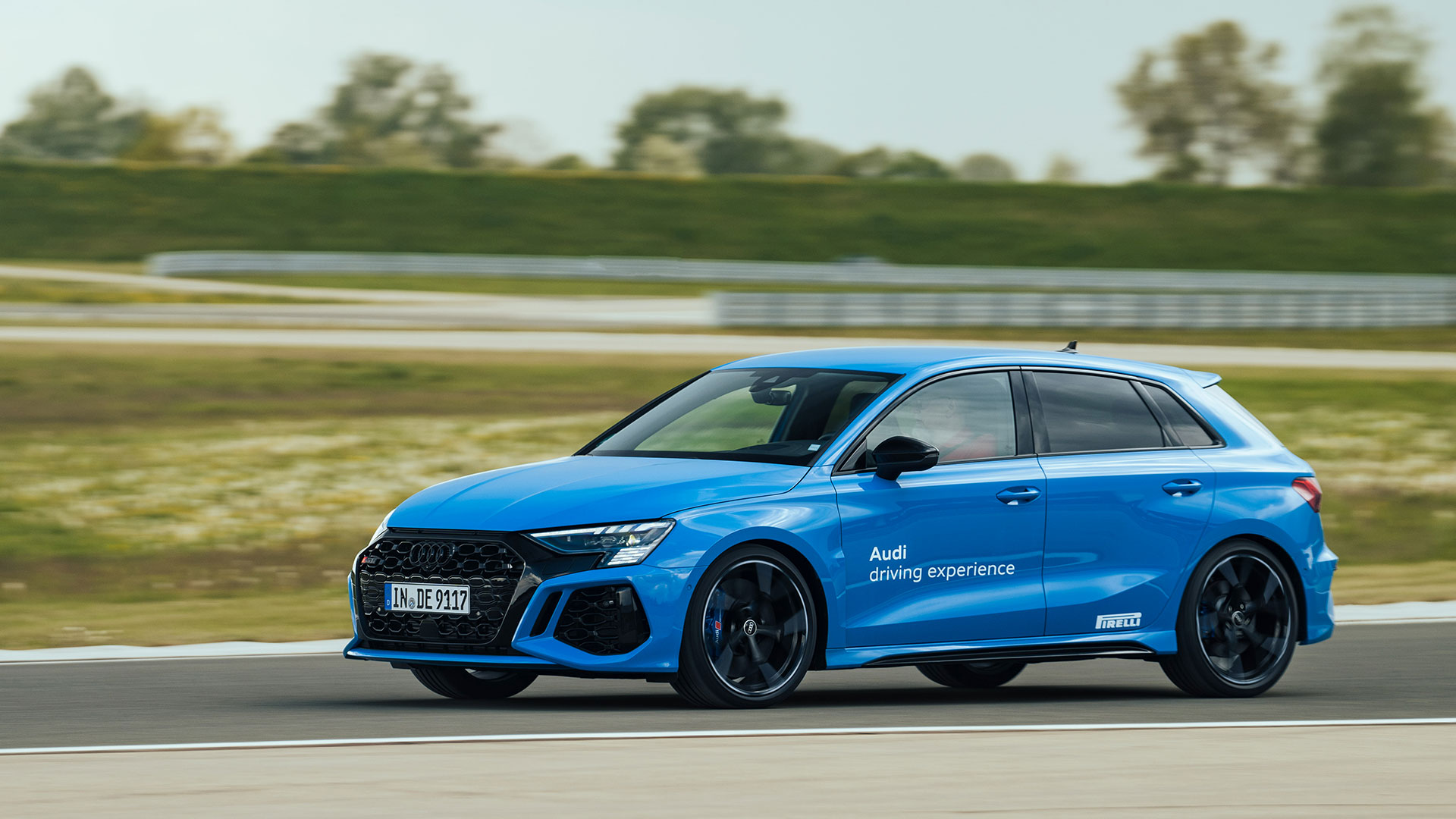 A blue Audi RS 3 Sportback in full swing on a race track