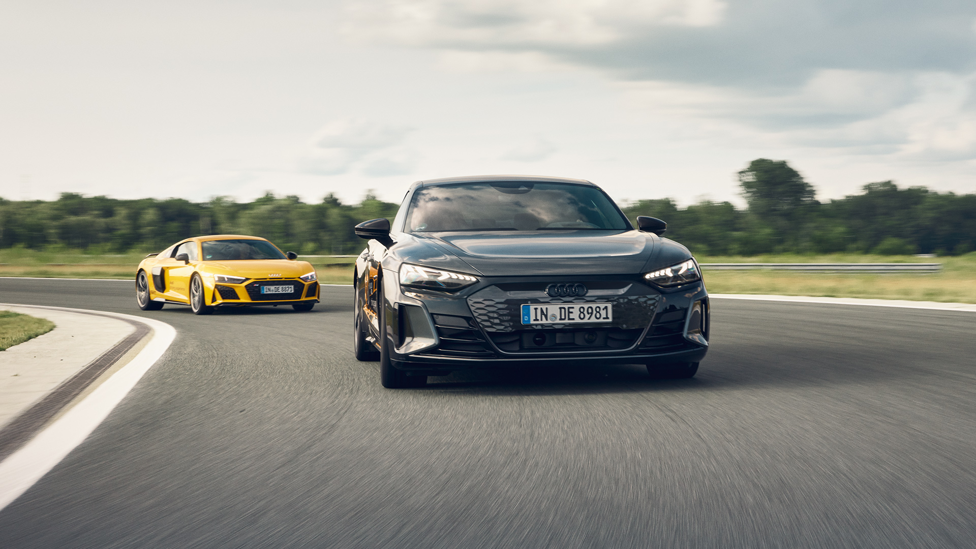 Yellow R8 Coupé V10 performance quattro and gray RS e-tron GT on the race track, RS e-tron GT leads the way