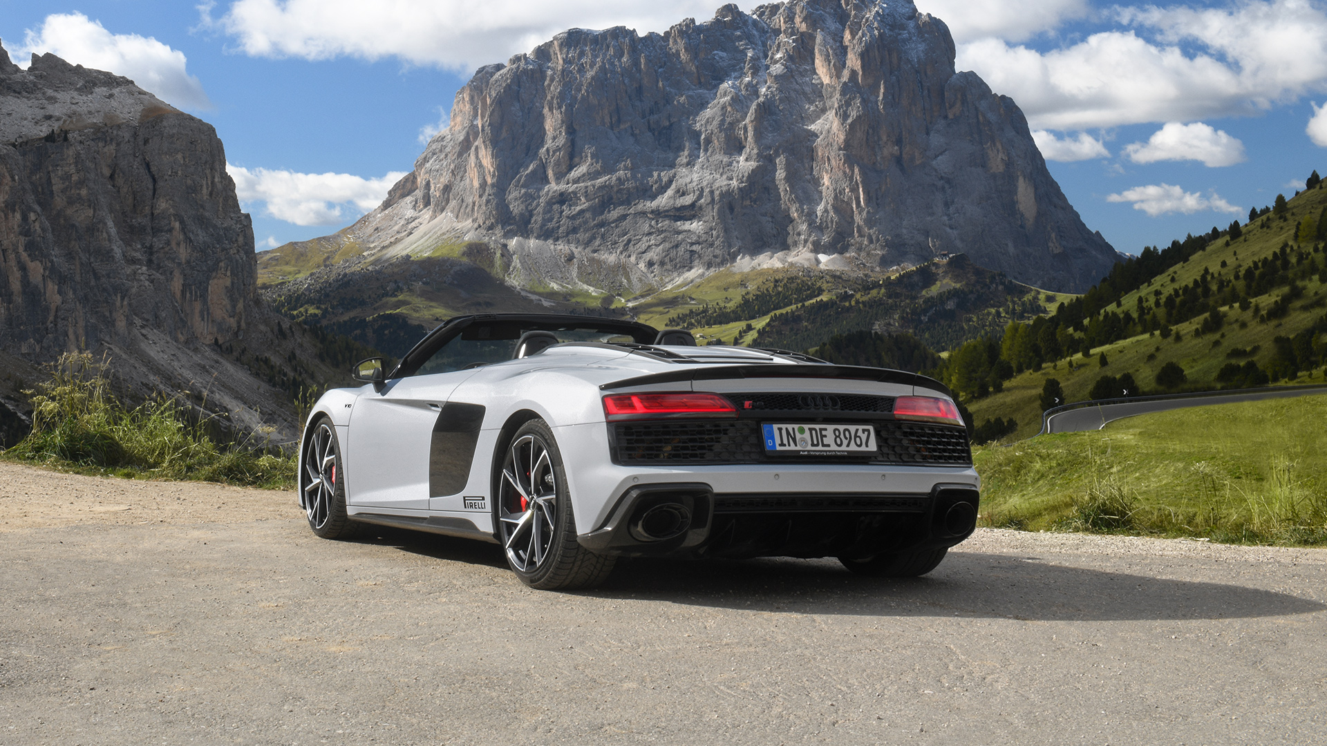 White Audi R8 Spyder V10 performance quattro with open top (rear view) stands in the mountains at best weather