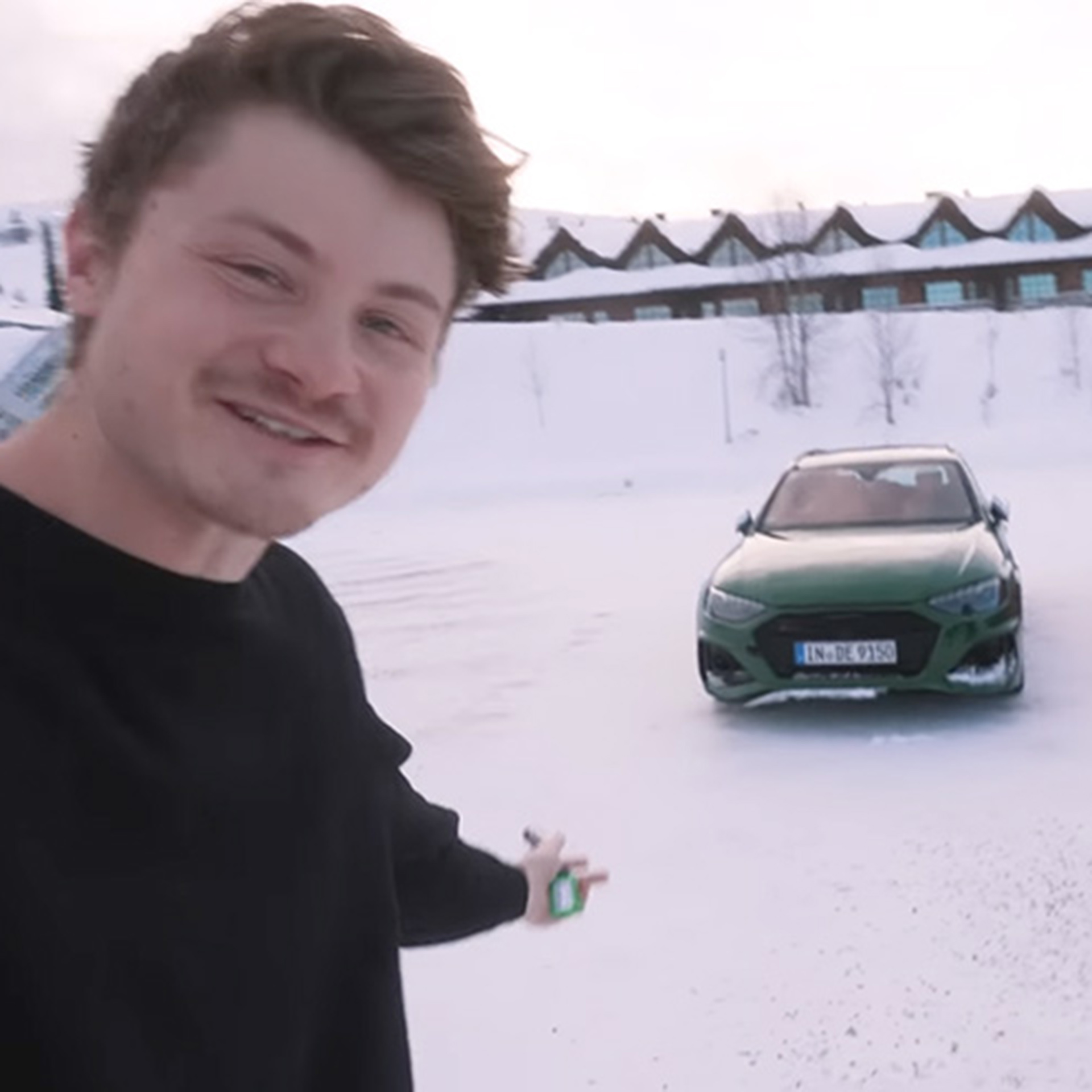 Youtuber Felix von der Laden steht vor einem dunkelgrünen Audi Modell im Schnee bei der Audi ice experience in Finnland