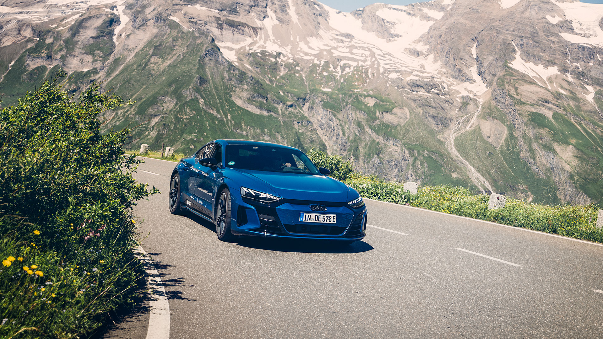 Blue Audi RS e-tron GT takes a bend through the mountains